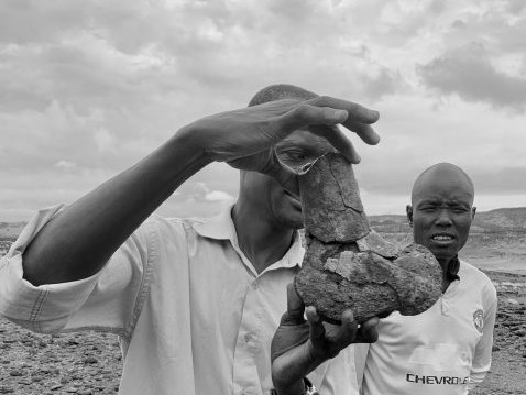 Francis Ekai Ikai, a fossil finder at the Turkana Basin Institute, holds up a fossil hippo femur from the Lothagam geologic formation, near Kenya’s Lake Turkana. Looking on, his colleague Julius Kerio. Credit: Sophia Lee