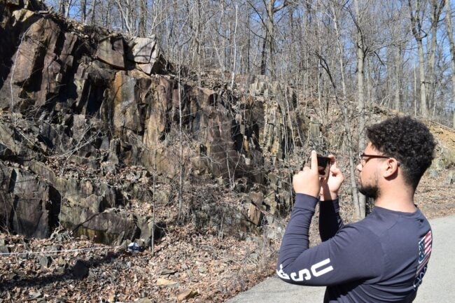 Man takes pictures of a cliff with a cell phone.