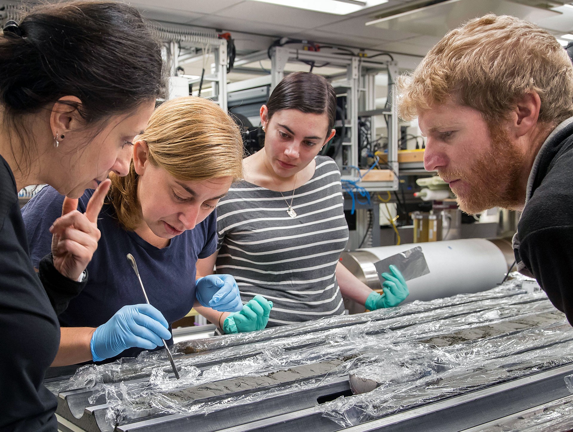 Scientists examine and describe a deep sea core retrieved on IODP Expedition 375 in the Hikurangi Subduction Margin. Credit: Tim Fulton, IODP/JRSO.