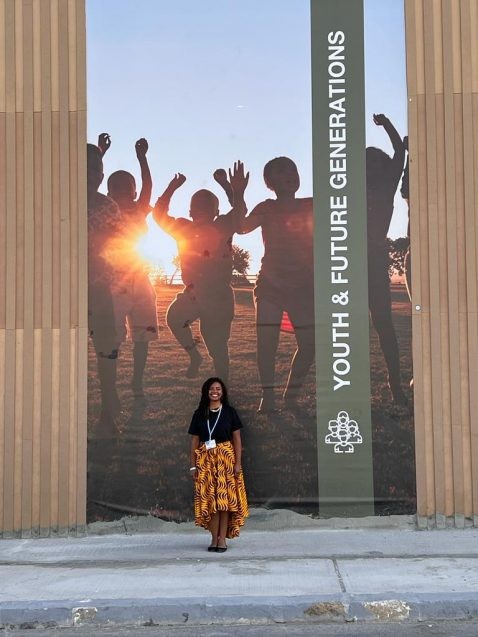 kristina douglass standing in front of a banner about youth and future generations