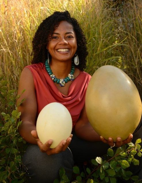 Researcher Kristina Douglass holds an elephant bird egg and an ostrich egg.