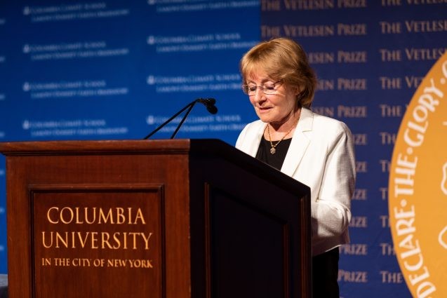 A formally dressed woman speaks at a podium