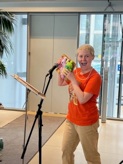 A person in an orange shirt holds up a DIY instrument