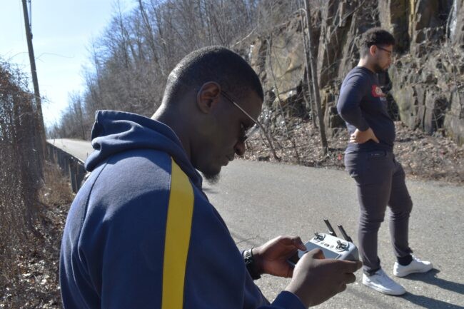 Man with console is piloting a drone.