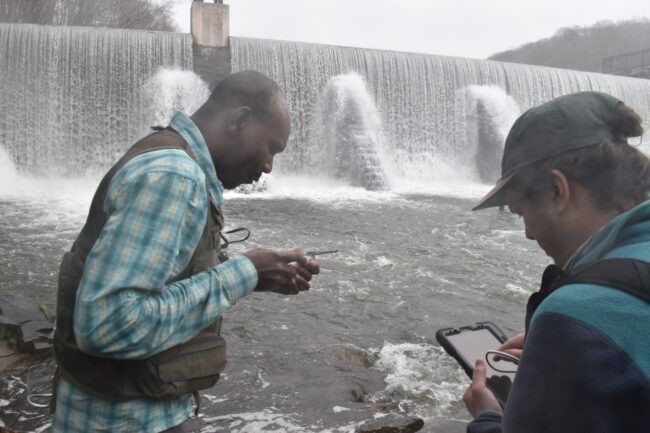 Two men in front of a dam.