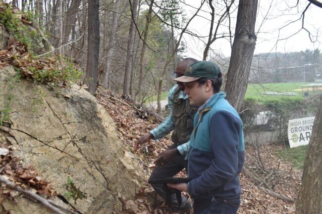 Two men examining a rock. 