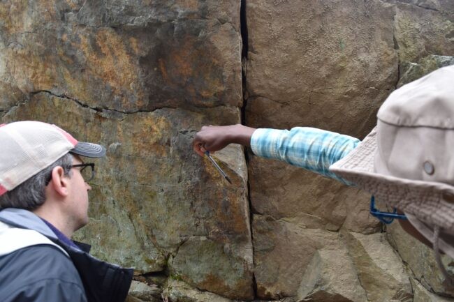 Two men looking at a cliff face.