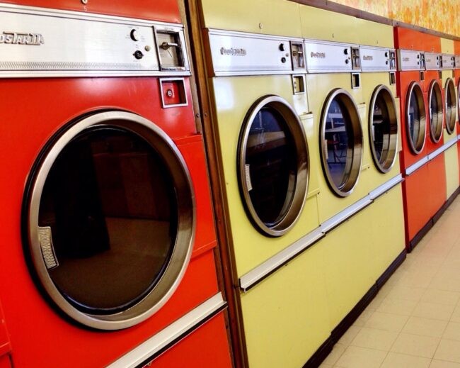 A row of brightly colored vintage washing machines