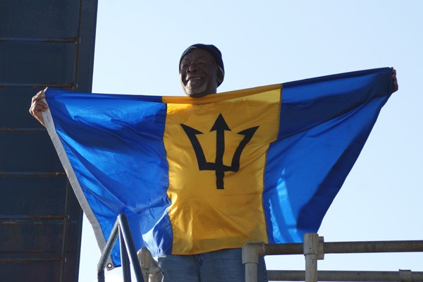 R/V Atlantis Wiper Leroy Walcott climbs out of the sub hoisting the flag of Barbados, which fittingly features a prominent trident symbol. Leroy is the first Barbadian to dive in Alvin. (Photo by Wanda Vargas)