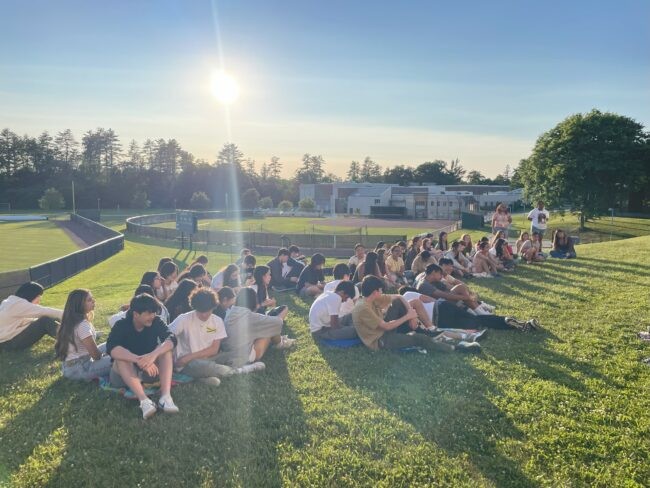 Students in a field with sun in background