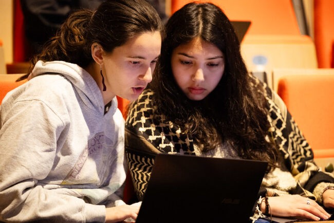 Two students look at a laptop