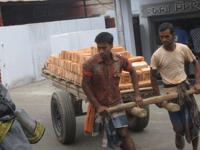 Men pulling cartful of bricks