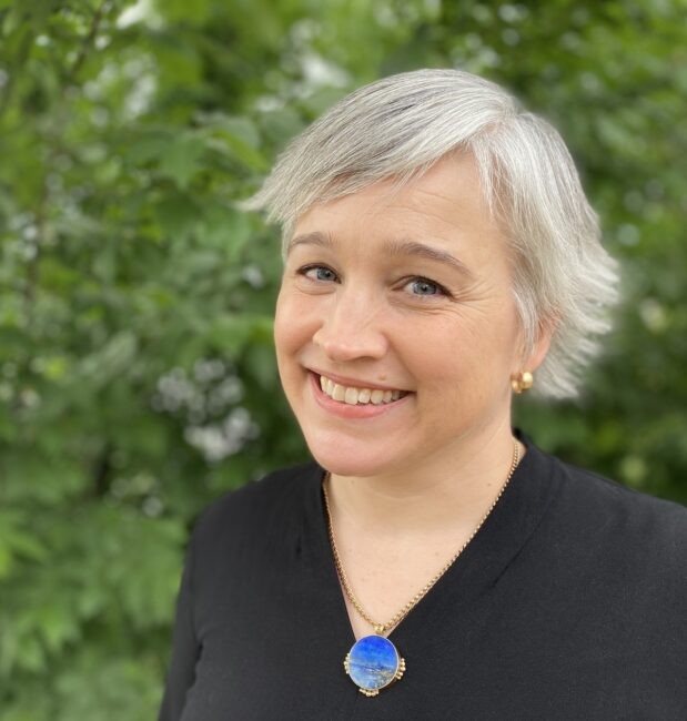 Woman smiling in front of trees