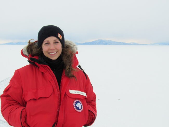 Woman in red coat and hat with ice in background