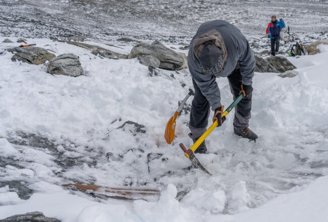 Man with ice pick in snow