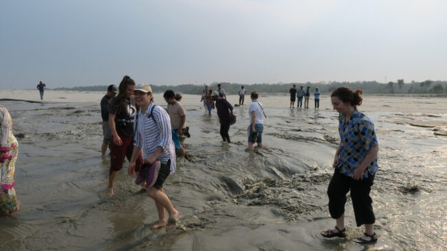 People wade into shallow water