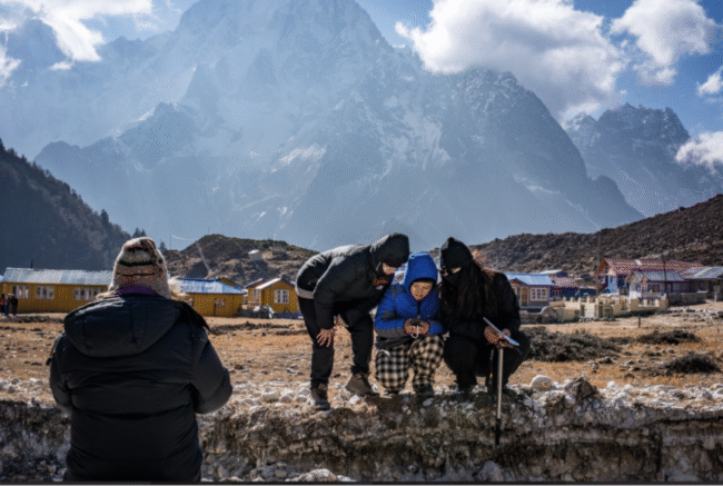 Researchers in winter gear gather coordinates in front of a mountain village