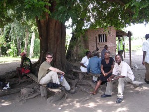 Jim, Loveness and Hassan wait under mango tree for go-ahead to install station