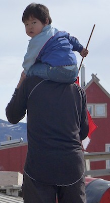 Community turns out to wait for helicopter. Child is holding a Greenlandic flag. (Photo M. Turrin)