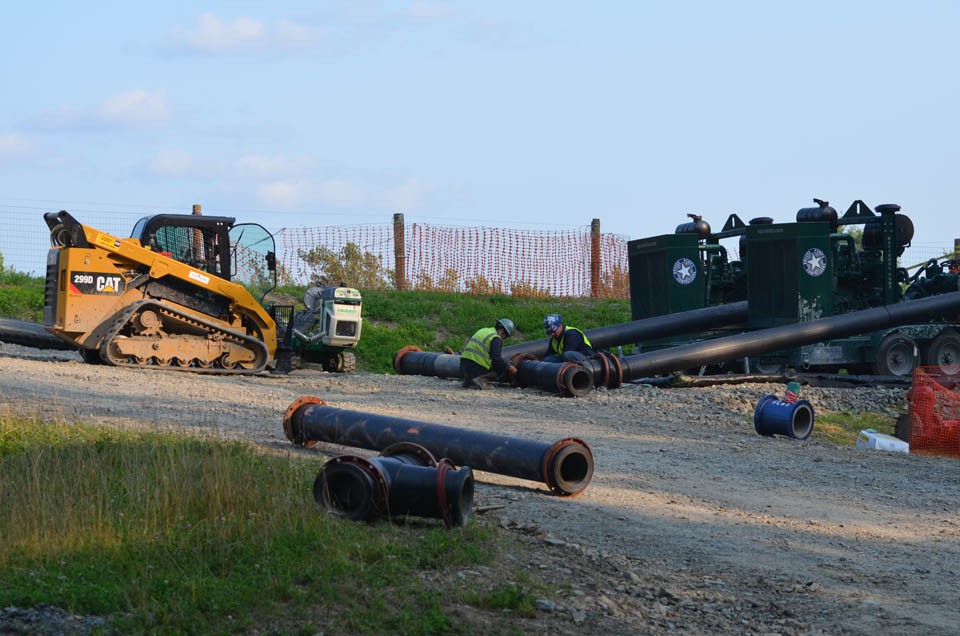 Setting up each well requires thousands of truckloads of material and machinery. Here, workers assemble pipe at a new well. 4