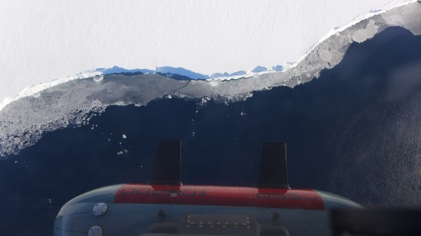 Icepod flying over the front of the Ross Ice Shelf. Along the shelf edge sections of thinner sea ice appear grey on the water surface. (Photo W. Chu) 