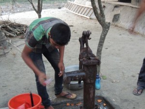 Collecting a water sample for testing arsenic levels at the well of the Islam family, host of the compaction meter. It came out clean.