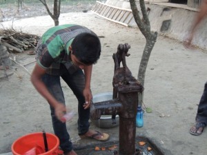 Collecting a water sample for testing arsenic levels at the well of the Islam family, host of the compaction meter.  It came out clean.