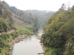 A small boat sailing up a scenic river in Mizoram.