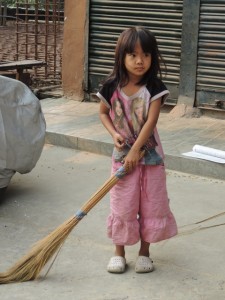 A little Mizo girl sweeping the street in front of her family's shop