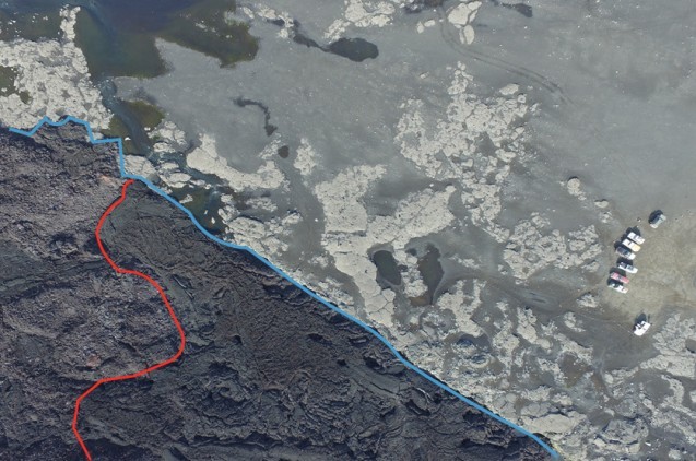 An aerial photo shows the edge of the Holuhraun lava flow (blue line), where the lava went over a combination of sand and bedrock. Two types of lava appear on either side of the red line: smooth pahoehoe on the right and rubbly a’a on the left.