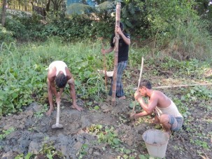 The three-person drill team preparing the site.  Digging a post hole with rebar, inserting the bamboo pole and digging the mud pit with a kudali.