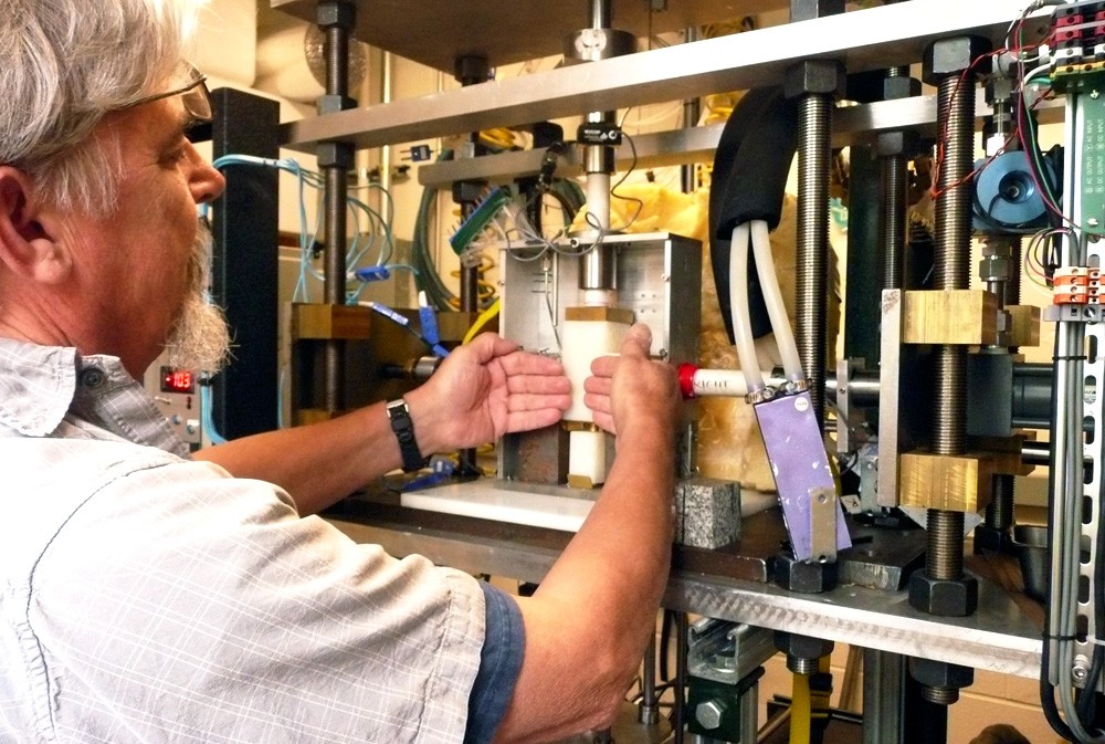 Research engineer Ted Koczynski explains how rock surfaces representing the rock bed of a glacier put pressure on a block of ice from each side as the ice is pushed downward in the new cryogenic deformation apparatus. Depending on the configuration, sensors throughout the device can measure friction, viscosity and anelasticity. Image: Lamont-Doherty Earth Observatory.