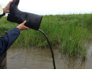 Tim emptying the muddy water from his boot.
