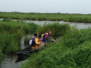 Tor and John paddle away from the site in a pirogue 