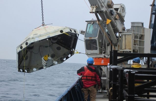 A shipboard crane lifts a Lamont-built ocean bottom seismometer attached to a protective trawler shield. Photo: Lamont-Doherty Earth Observatory
