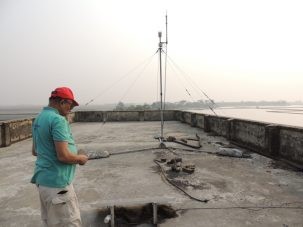 Humayun inspecting our equipment on the roof of a school on Polder 32. The tower is a meteorological station and our GPS antenna is on the back wall.