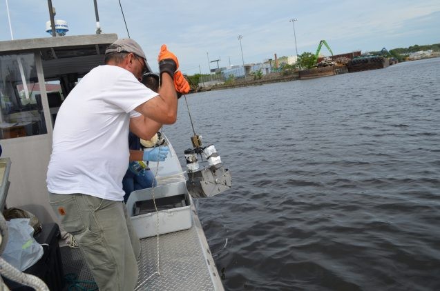 Captain John Lipscomb hauls a scoop of muck from the bottom of Newtown Creek. 