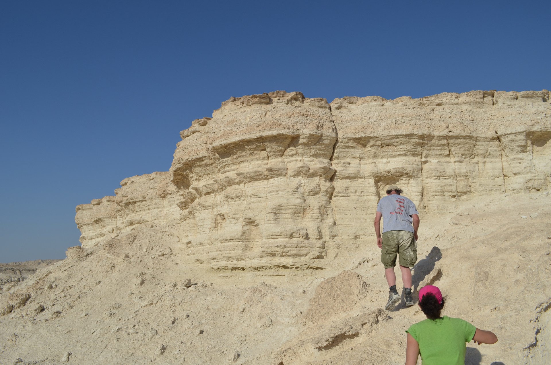 Kiro and Mordechai Stein of the Geological Survey of Israel approach a Cliffside deposit in the Israeli desert.