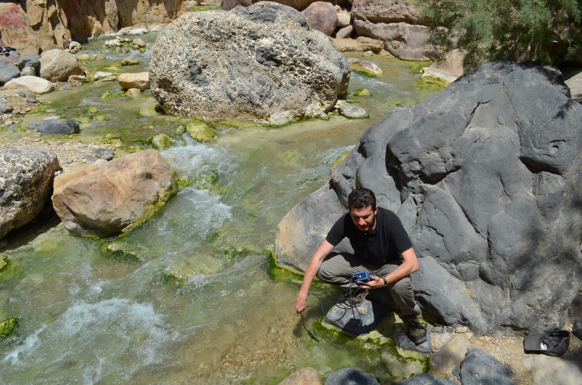 Mohamad Alqadi, a Jordanian PhD. student at the University of Munich, tests pH and temperature of stream water in a canyon.