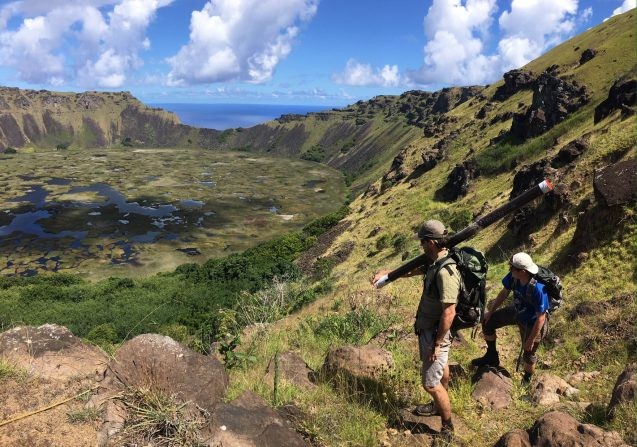 scientists approaching lake carrying sediment coring tubes on Easter Island