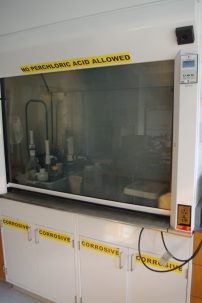 Chemical fume hood, with a plexiglass cover and lots of bottles and pumps behind it.