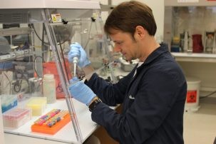 scientist pipetting under a hood