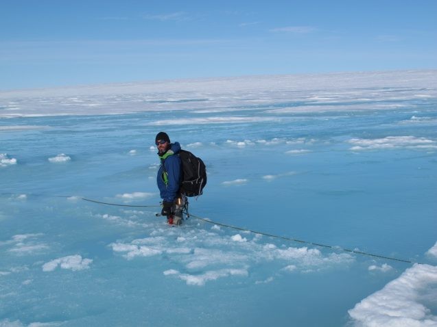 scientist stands in melting ice in Greenland