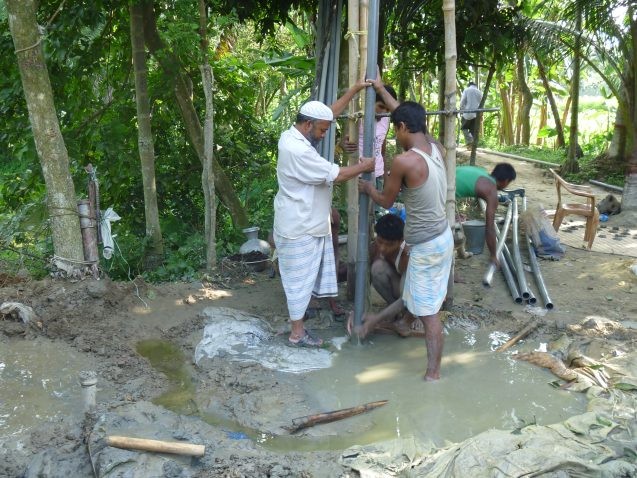Workers install a monitoring well