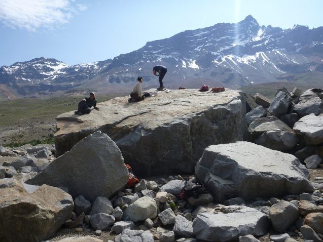 scientists sitting on large boulder