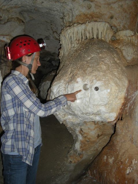 scientist points to hole drilled in cave wall
