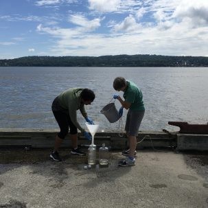 two women researchers pouring water into containers