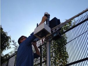 scientist installing a sensor near a fence