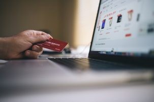 computer screen and hand holding a credit card