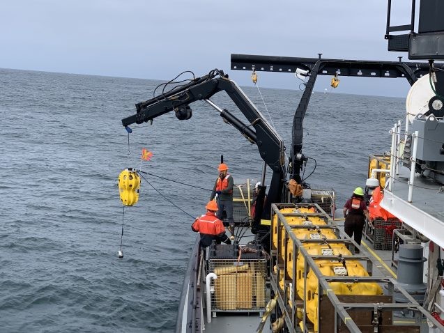 a crane lifts a yellow sensor out of the ocean